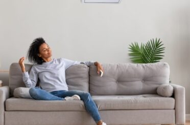 woman sitting on her couch enjoying the comfort of her air conditioning