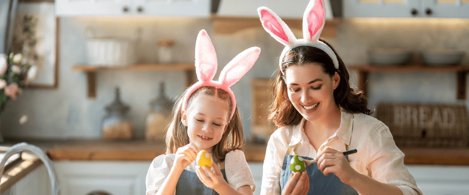 A mother and daughter wear bunny ears and paint Easter eggs
