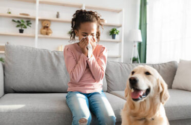 girl sneezing inside because of allergens in the air