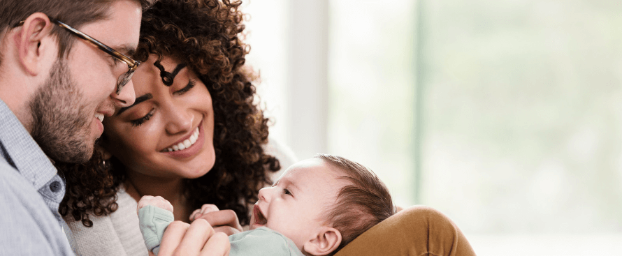 A couple cuddles their smiling baby