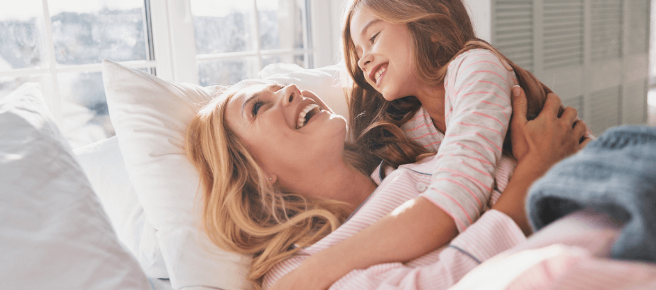 A mother and daughter cuddle and laugh