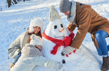 a family outside building a snowman at their home with an HVAC system