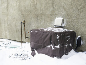 An HVAC unit covered in the winter protects from snow and ice.
